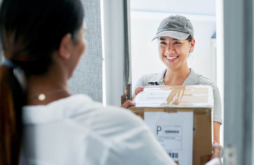 A delivery woman handing a package to a customer
